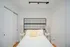 Bright and cozy bedroom featuring modern lighting, stylish black grid headboard, and soft white bedding with a touch of yellow.