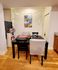 Cozy dining space with a modern black table, stylish artwork, and charming string lights, perfect for intimate gatherings.