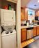 Contemporary kitchen and laundry combo with sleek wooden cabinets and modern appliances, offering stylish convenience.