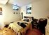 Cozy bedroom with warm wooden flooring, stylish wall decor, and abundant natural light through elevated windows.