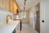 Modern kitchen featuring sleek stainless steel appliances, elegant gold fixtures, and stylish wooden cabinetry, illuminated by contemporary track lighting.