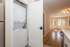 Chic apartment view featuring a modern laundry area with stacked washer and dryer, open living space, and large, sunlit bay windows.