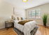 Inviting bedroom with plush bedding, warm decor, and abundant natural light from large windows, offering a cozy and tranquil retreat.