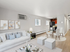Chic open-plan living and dining area with contemporary furnishings, stylish artwork, and a modern kitchen, illuminated by natural light.