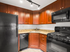 Modern kitchen with elegant cherry wood cabinets, sleek black appliances, and granite countertops.