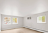 Bright and airy room featuring large windows, sleek wooden flooring, and a modern wall-mounted air conditioner.
