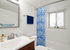 Elegant bathroom with modern fixtures, featuring a stylish blue patterned shower curtain, large vanity mirror, and ambient natural light.