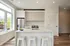 Bright, modern kitchen with sleek white cabinetry, stainless steel appliances, and a chic island with bar seating, perfect for entertaining.