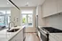 Elegant modern kitchen with sleek white cabinetry, stainless steel appliances, and large windows offering ample natural light.