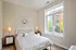 Bright and cozy bedroom with a large window showcasing urban views, complemented by modern furnishings and stylish decor.