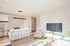 Bright open-concept living space with modern kitchen, stylish seating, and sleek TV setup, perfect for entertaining.