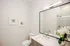 Elegant bathroom featuring a modern vanity with dual faucets, a large mirror, and decorative wall art, accented by a bouquet of white flowers.
