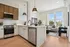 Bright and modern kitchen with sleek white cabinets, a stylish island, and cozy living area featuring large windows and elegant decor.