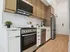 Modern kitchen with sleek appliances, stylish cabinetry, and elegant wood flooring for a contemporary living experience.