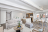 Modern living space featuring an open-concept layout with a cozy sofa, stylish kitchen with wooden cabinets, and a bright dining area illuminated by large windows.