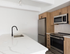 Cheesman Park, CO, apartments near Molly Brown House Museum - The Grove on York - Modern Kitchen With Single-Sink Island, Black Faucet, Wood Cabinets, and Stainless Steel Appliances.