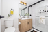 Cheesman Park, CO, apartments near Denver Botanic Gardens - The Grove on York - Modern Bathroom With Wood Vanity, Black Fixtures, Large Mirror, and Glass Shower With White Tile.