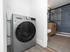 Modern apartment featuring a sleek in-unit washer and a contemporary bathroom with stylish blue tile and wooden accents.