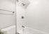 Bright, modern bathroom with sleek fixtures, white tiles, and a contemporary bathtub.