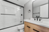 Modern bathroom featuring sleek black fixtures, glass-enclosed shower, and stylish wood vanity.