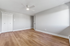 Bright and spacious bedroom with elegant wood flooring, fresh white walls, and a modern ceiling fan, perfect for creating your cozy retreat.