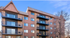 Charming apartment building with spacious balconies and modern exterior design, set against a clear blue sky.