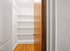 Inviting walk-in closet with sleek wooden flooring, ample shelving, and classic design, perfect for organized living.