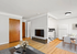 Inviting open-plan living area with elegant hardwood flooring, modern kitchen appliances, and a stylish dining setup, perfect for cozy family gatherings.