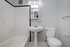 Sleek and modern bathroom with a clean white bathtub, pedestal sink, and bright lighting perfect for a refreshing start to your day.