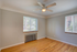 Bright and airy room with large windows, sleek ceiling fan, and beautiful hardwood floors, perfect for a cozy living space.