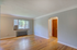 Bright and open living space with hardwood floors and a large window letting in natural light, complemented by neutral-colored walls in a welcoming apartment.