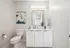 Elegant bathroom with modern fixtures, featuring a sleek white vanity, large mirror, and contemporary art piece.