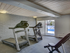Contemporary fitness room with modern treadmills and exercise benches, featuring natural light from sliding glass doors leading to an outdoor pool area.