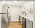 Modern kitchen with sleek stainless steel appliances, elegant white cabinets, and a stylish wooden floor.