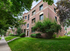 Charming red-brick apartment building with lush greenery and a welcoming entrance, perfect for urban living.