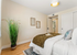 Inviting bedroom with elegant decor, large plant, cozy bedding, and tasteful artwork, creating a relaxing, modern atmosphere.