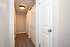 Welcoming hallway with sleek wood flooring and elegant white doors, perfect for a stylish apartment entrance.