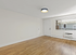 Bright, open living space with sleek hardwood floors and large window providing natural light.