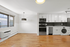 Bright and modern kitchen with white cabinetry, stainless steel appliances, and sleek hardwood floors, perfect for stylish urban living.