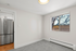 Bright and inviting room with ample natural light, showcasing a sleek stainless steel refrigerator and plush carpeting, ideal for modern living.
