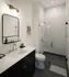 Elegant modern bathroom with sleek black vanity, marble countertop, and glass-enclosed shower, showcasing contemporary design and functionality.