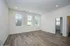 Bright and airy living space with elegant wood flooring, recessed lighting, and large windows overlooking greenery.