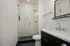 Elegant bathroom featuring a sleek glass-enclosed shower, modern vanity with dual sinks, and chic black fixtures.
