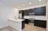 Modern kitchen with sleek dark cabinets, stainless steel appliances, elegant white countertops, and warm hardwood flooring.