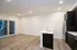 Modern open-concept apartment with elegant hardwood floors, sleek kitchen featuring dark cabinetry, and ample natural light from large sliding doors.