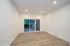 Bright and inviting living space with elegant laminate flooring, recessed lighting, and large sliding glass doors leading to a serene outdoor view.
