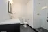 Modern bathroom featuring sleek white countertop, hexagonal tile flooring, and a spacious glass-enclosed shower.