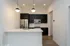 Modern kitchen with sleek black cabinets, stainless steel appliances, and elegant pendant lighting over a spacious island.