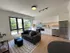 Bright and modern apartment living area with sleek open-plan kitchen, cozy sofa, and large window inviting natural light.