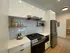 Modern kitchen with sleek white cabinets, stainless steel appliances, and elegant open shelving in a stylish apartment.